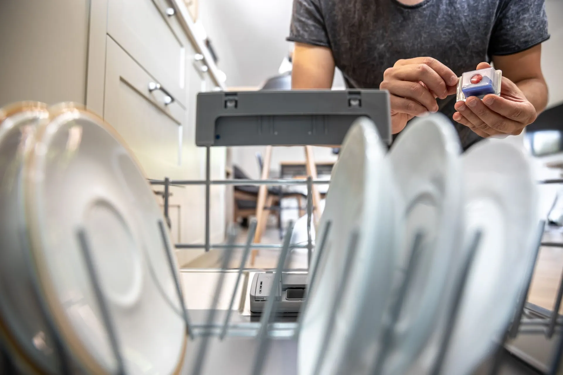 Technician loading detergent into an open dishwasher